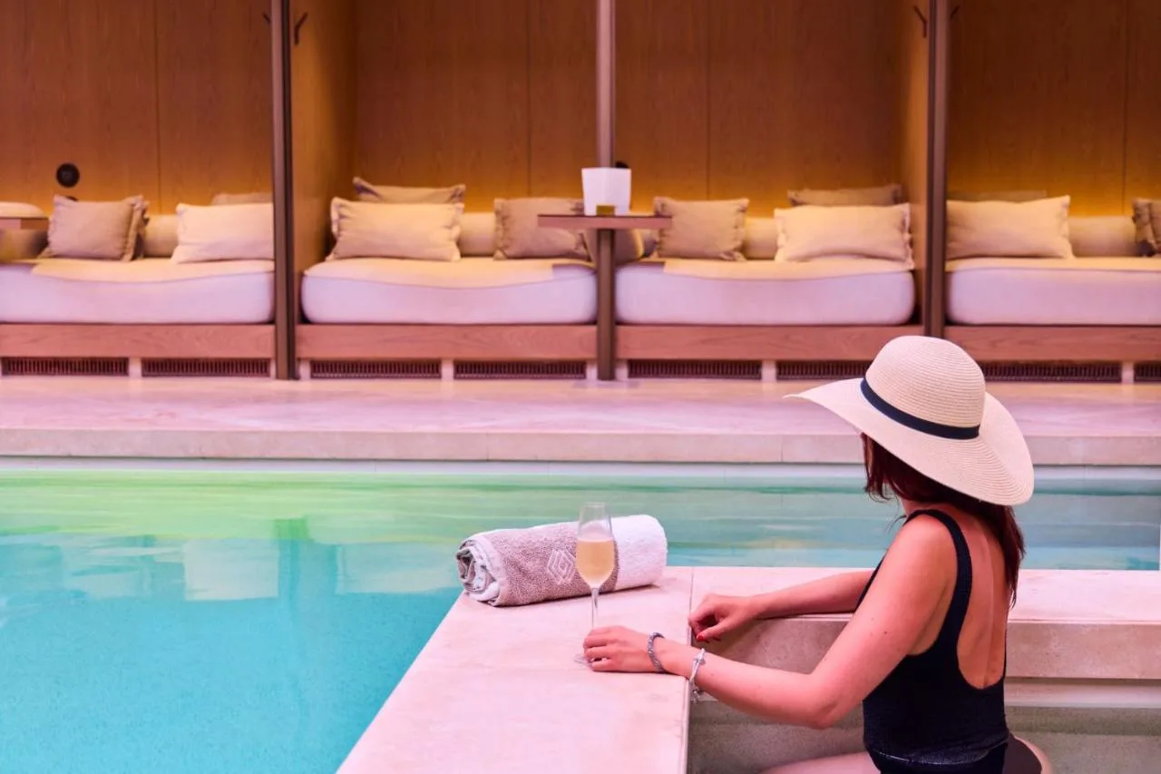 a woman in a hat sitting next to a swimming pool at The Londoner in London